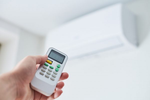 Remote control for air conditioner in hand. Room condition remote control. Air temperature switch for cooling of space.